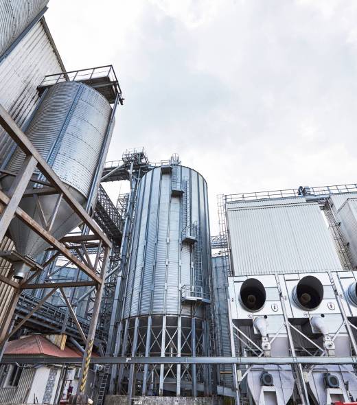 Agricultural Silos. Building Exterior. Storage and drying of grains, wheat, corn, soy, sunflower against the blue sky with white clouds.